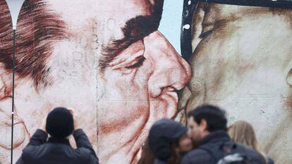 Una persona toma fotos a una pintura que representa el ex líder soviético Leonid Brezhnev besando a su homólogo alemán oriental Erich Honecker.