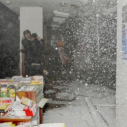 Dos personas se protegen de la caída del techo en una librería de Sendai.