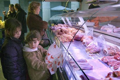 Dos niñas ante el puesto de una pollería en el mercado de La Boquería, en Barcelona.