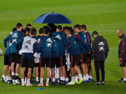 Los jugadores españoles, protegidos de la lluvia con un paraguas en un entrenamiento en el estadio de Gran Canaria.