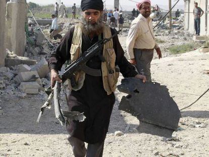 Un miembro del EI lleva un pedazo de un avi&oacute;n ca&iacute;do en Raqa (Siria).