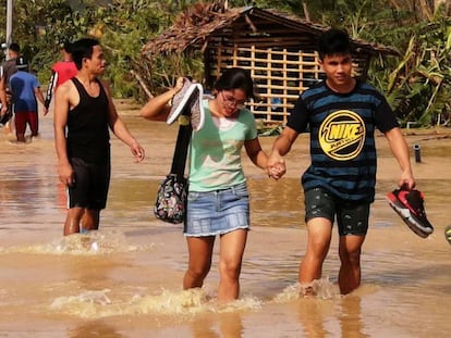 Un grupo de personas atraviesa una carretera inundada este jueves en Ormoc (Filipinas). En vídeo, imágenes del tifón Phanfone a su paso por el país del sudeste asiático.