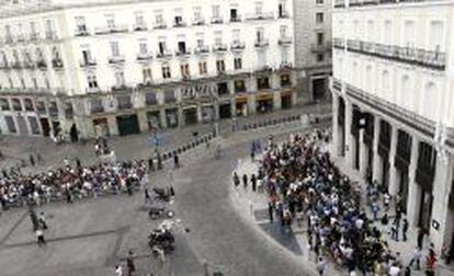 Numerosas personas esperan a la entrada de la Apple Store en la Puerta del Sol que abre hoy sus puertas al p&uacute;blico.