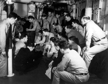 Los principales suboficiales del buque escuchan la emisión de radio del discurso del presidente Franklin D. Roosevelt —ante el Congreso— solicitando una declaración de guerra contra las potencias del Eje, el 8 de diciembre de 1941.