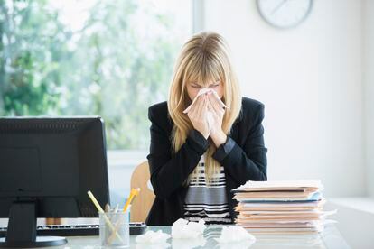 Businesswoman blowing her nose in the office