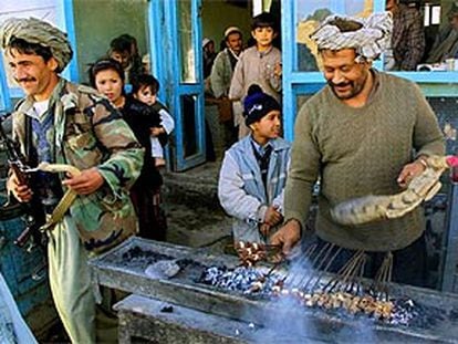 Un afgano prepara pinchos de carne al estilo tradicional ante una casa, en Mazar-i-Sharif.