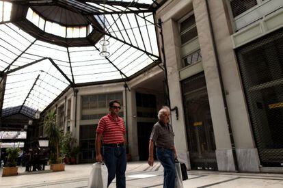 Dos hombres caminan por un centro comercial en Atenas.