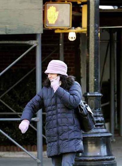 Una mujer habla por el móvil mientras cruza una calle de Nueva York