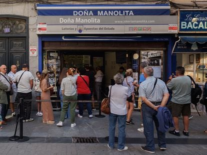 Varias personas hacen cola para comprar en la administración de loterías Doña Manolita, en Madrid (España).