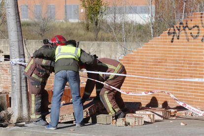 Els bombers treballen a la zona on ha caigut el mur a causa del vendaval, a Terrassa (Barcelona).
