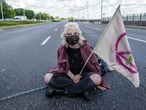 An environmental activist of Extinction Rebellion Youth group (XR) forms a chain to block one of the main street in the city centre in Warsaw, on May 24, 2021, to draw public attention to the climate crisis and global warming. (Photo by Wojtek RADWANSKI / AFP)