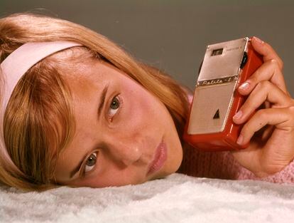 1950s 1960s Teenage Girl Holding Red Silver Small Transistor Radio To Her Ear Listening