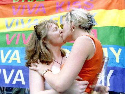 Dos mujeres se besan al lado de una pancarta reivindicando los derechos de la comunidad gay en una marcha en Londres.