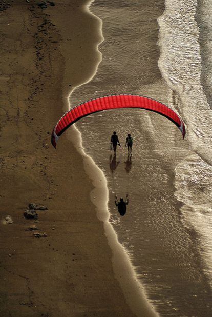 Un parapente sobrevuela la playa de Torimbia, en Llanes (Asturias).