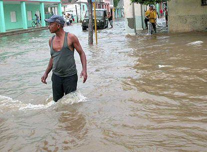 Un hombre camina por una calle inundada en la localidad de Mayarí (este de Cuba), tras el paso del Ike.