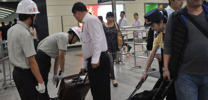 Personal de seguridad revisan este mi&eacute;rcoles los equipajes de los pasajeros en la estaci&oacute;n de trenes de Guangzhou.