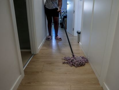 Una empleada de hogar limpia una vivienda con una fregona.