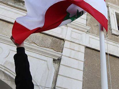 Un empleado coloca la bandera libanesa en la embajada abierta ayer por primera vez en Damasco.