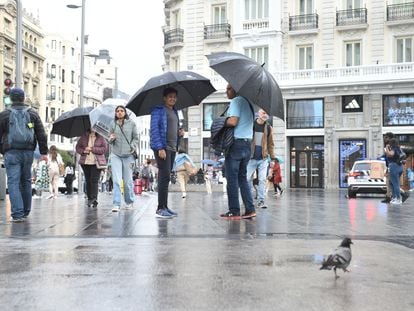 Varias personas pasean bajo la lluvia, el martes 23 de mayo, en el centro de Madrid.