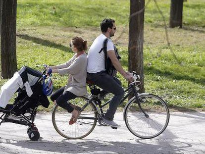 Una pareja pasea en bici con el carrito del bebé. EFE/Archivo