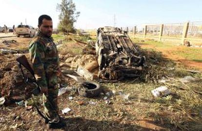 Un miembro de las fuerzas de seguridad libias junto a los restos de un coche con el que un terrorista suicida embistió un control el pasado 22 de diciembre en Bengasi.