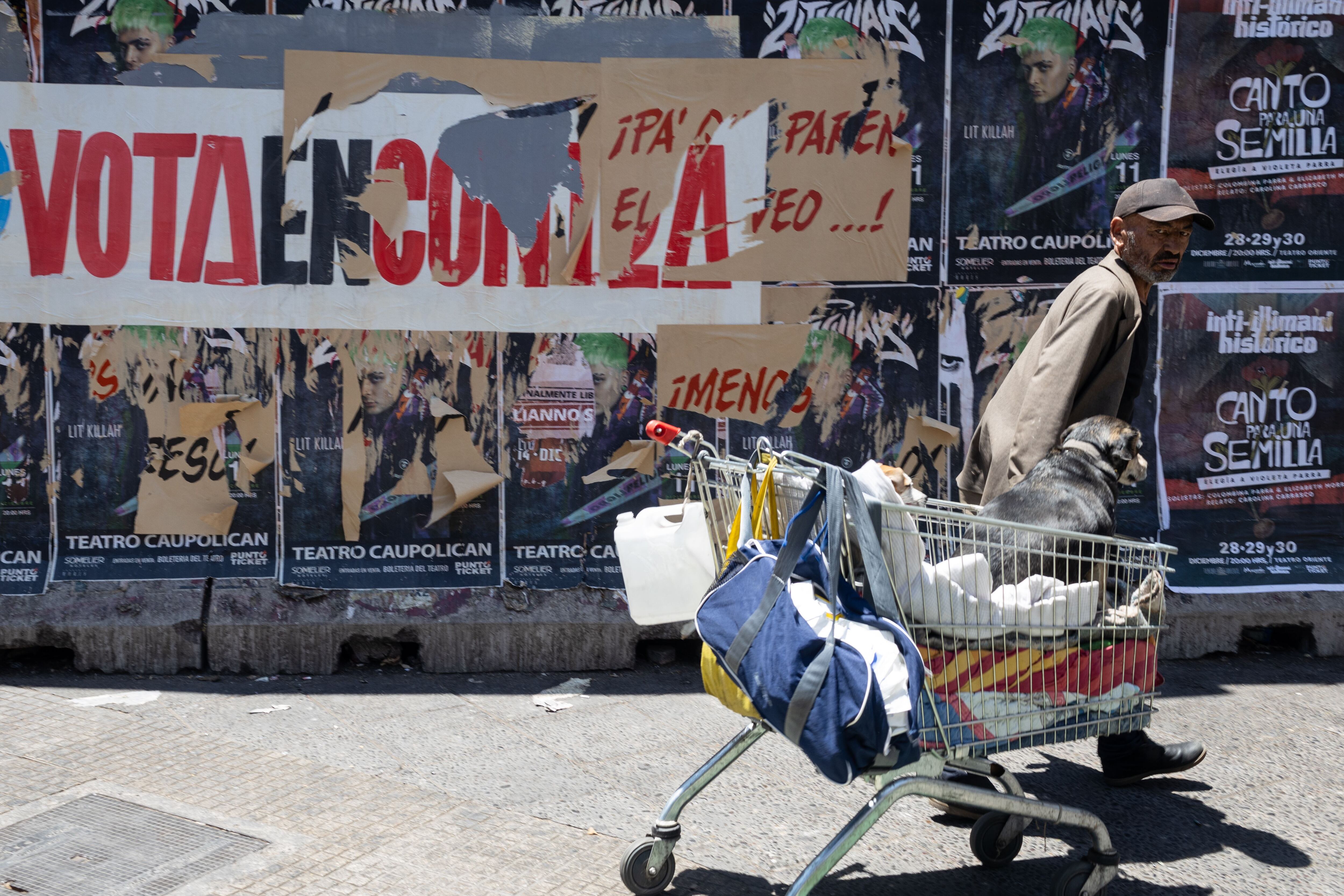 Una persona camina frente a un cartel rasgado de la campaña por el 'en contra', el 13 de diciembre en Santiago.