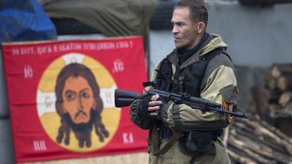 Un rebelde ucranio, ayer en Donetsk ante una bandera del Batall&oacute;n Ortodoxo Ruso