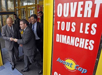 El ex ministro francés de Trabajo, Xavier Bertrand, sale de un centro comercial de Marsella en un domingo del pasado mes de abril junto a un cartel que reza "abierto todos los domingos".