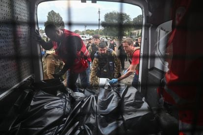 Red Cross volunteers place the bodies of people killed by the Russian attack.