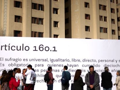 Un grupo de personas pasea frente a una gigantografía con un artículo de la Constitución propuesta en Chile, este martes en Santiago.