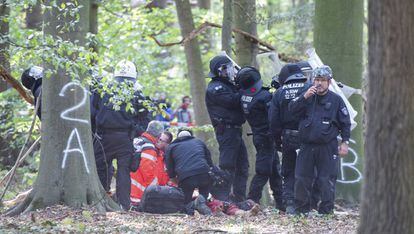 Sanitarios y policías atienden al hombre caído de una pasarela entre árboles en el bosque de Hambach. 