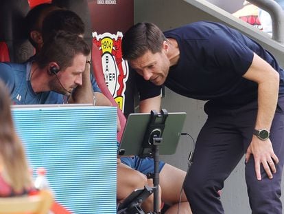 Xabi Alonso, entrenador del Bayer Leverkusen observando un dispositivo junto a su asistente.