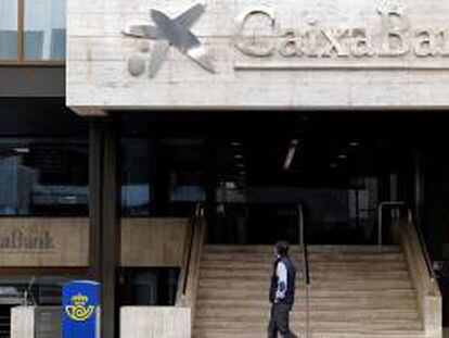 Un hombre observa el logo de Caixabank que desde ayer sustituye al de Bankia, tras la fusión de ambos bancos.