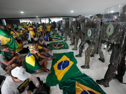Simpatizantes de Jair Bolsonaro, sentados frente a la policía tras su asalto al palacio de Planalto, el día 8 en Brasilia.
