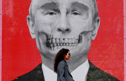 Una mujer pasa delante de un retrato del presidente ruso, Vladímir Putin, caracterizado como una calavera, durante una exposición en contra de la ofensiva militar rusa en Ucrania, en la plaza del Rey de Bucarest (Rumania) el 29 de abril.