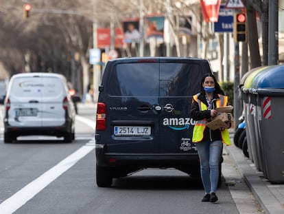 Una repartidora de Amazon carga con varios paquetes mientras tiene la furgoneta en el carril bus de Travessera de les Corts.