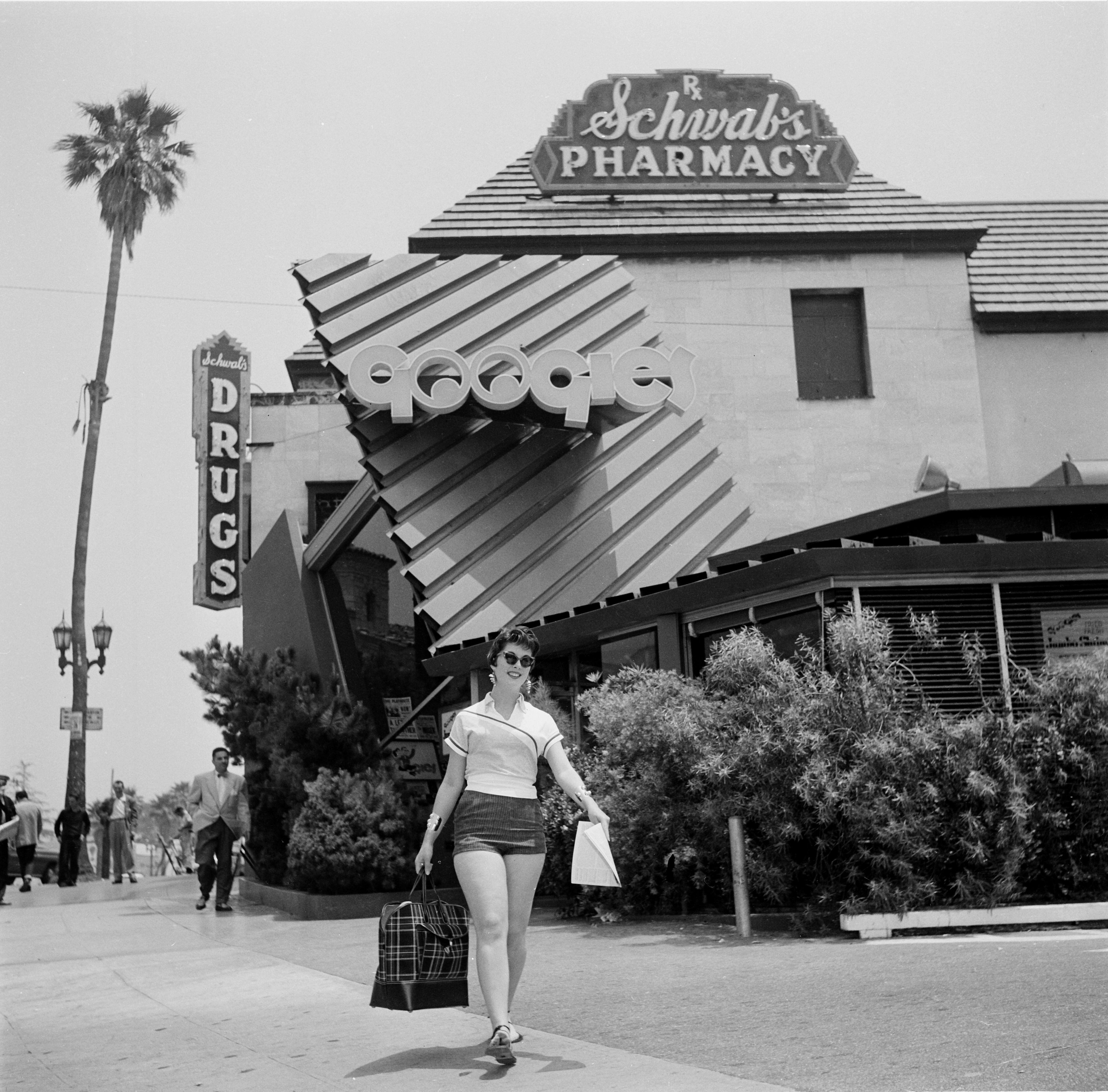 Una mujer camina frente a Googies Coffee Shop en Los Ángeles en 1954.
