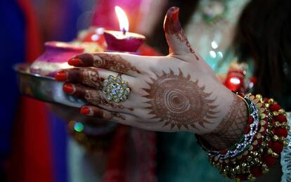 Una mujer casada sostiene una vela en un ritual para pedir longevidad y bienestar a su marido, este domingo en Jammu (India).