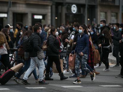 Decenas de personas cruzan el paso de peatones que comunica plaza Catalunya con la Rambla en Barcelona