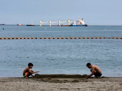 Un niño y un hombre juegan en una playa de Gibraltar este pasado jueves, tras el vertido provocado por el accidente del granelero 'OS35'.