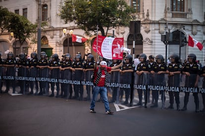 Un manifestante levanta un cartel con los colores de la bandera peruana frente a policías antidisturbios, durante una protesta el 16 de diciembre de 2022.