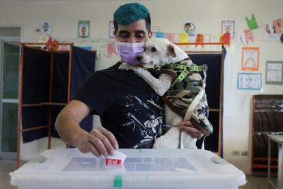 Un ciudadano sostiene a un perro mientras deposita su voto en una urna en Santiago.