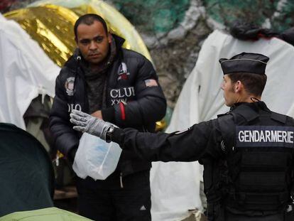 Un agente francés hace un gesto a un migrante durante el desalojo de un campo en el centro de París, el pasado 4 de junio.