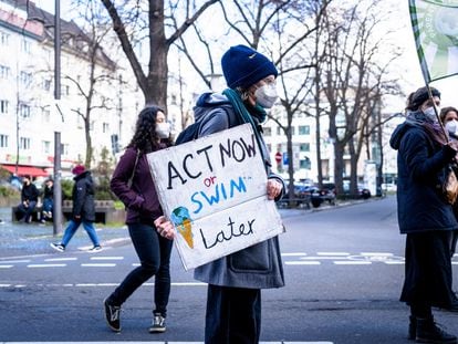 Un manifestante participa en una concentración por el clima, con una pancarta que dice "Actúa ahora o nada después".