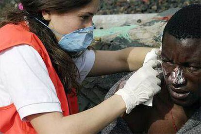 Una voluntaria de Cruz Roja aplica pomada en las quemaduras solares de uno de los 31 inmigrantes.