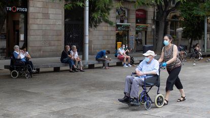 Una mujer pasea a un señor en silla de ruedas, el año pasado en el centro de Barcelona.