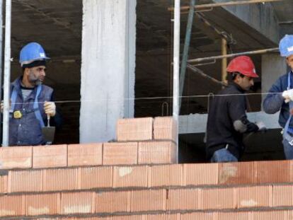 Tres obreros trabajan en la construcci&oacute;n de una vivienda. 