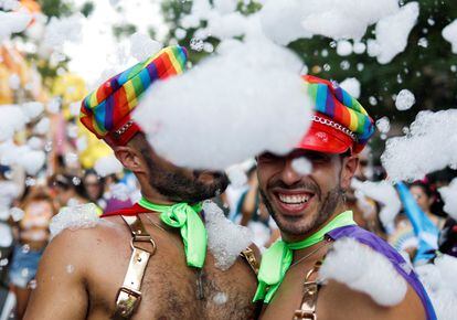 Dos hombres se refrescan con espuma en la marcha del orgullo en Madrid. 