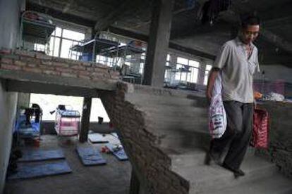 Un trabajador inmigrante carga con sus pertenencias en el interior de un edificio en obras utilizado como hostal barato para trabajadores inmigrantes en la ciudad china de Linyin. EFE/Archivo