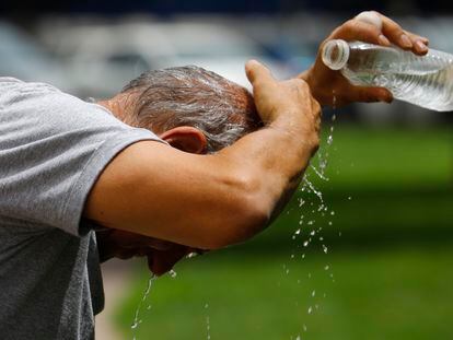 Un hombre se refresca con una botella de agua en el centro de Córdoba.